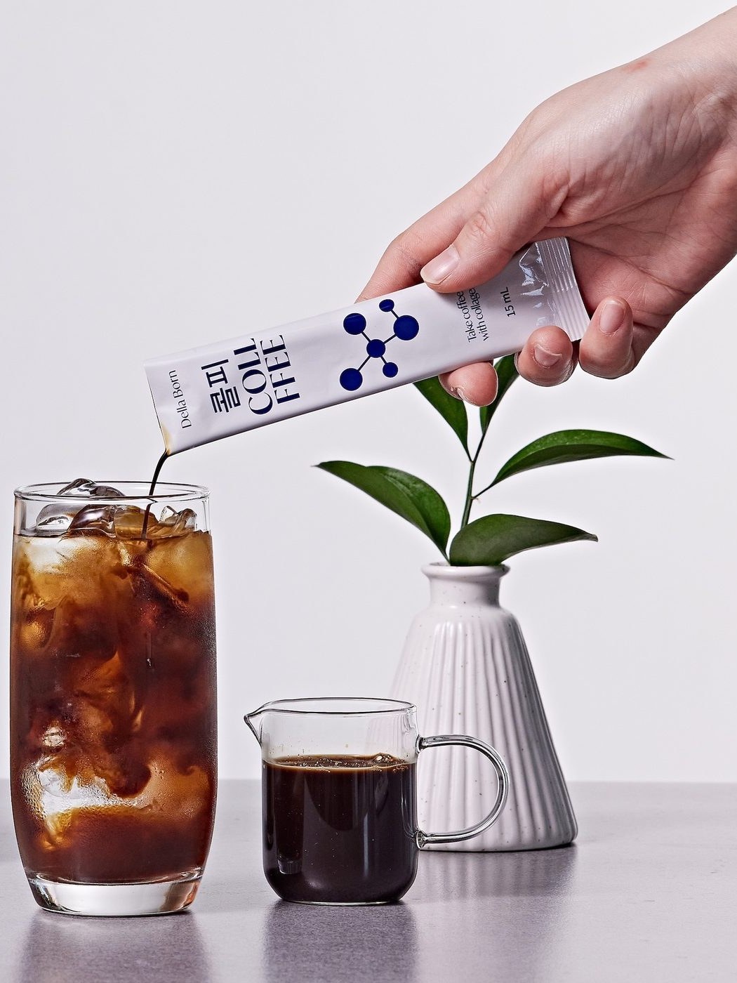 Pouring a stick into iced coffee beside a vase