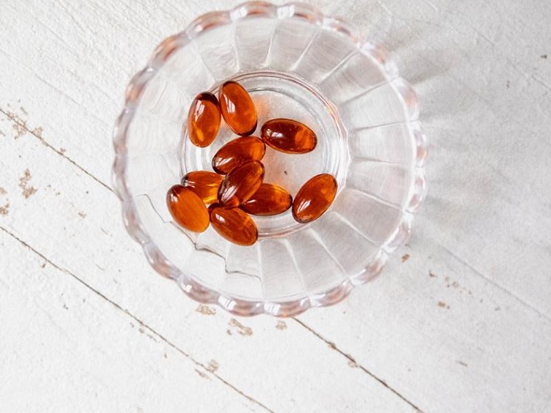 Amber softgels in fluted glass bowl